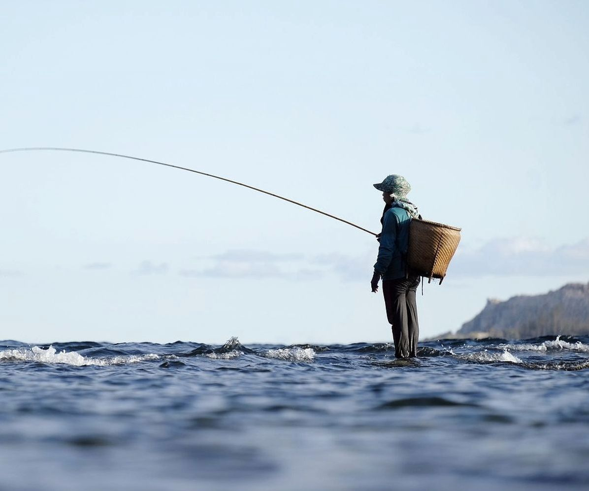 Mãos preparando o equipamento de pesca na beira do lago