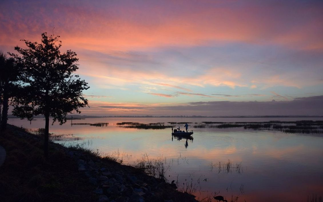 Um pescador ao amanhecer nas águas do lago de montanha